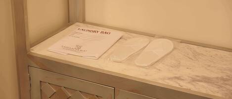 A bathroom with a marble countertop, a pair of slippers, and a 'Laundry Bag' sign.