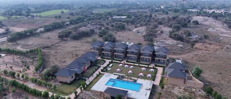 A large resort with multiple buildings, a swimming pool, and landscaped gardens.