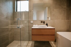 A modern bathroom with a glass shower enclosure, a wooden vanity with a sink, and a bathtub. - Luxury House with Private Spa & Mountain Views (Wanaka)