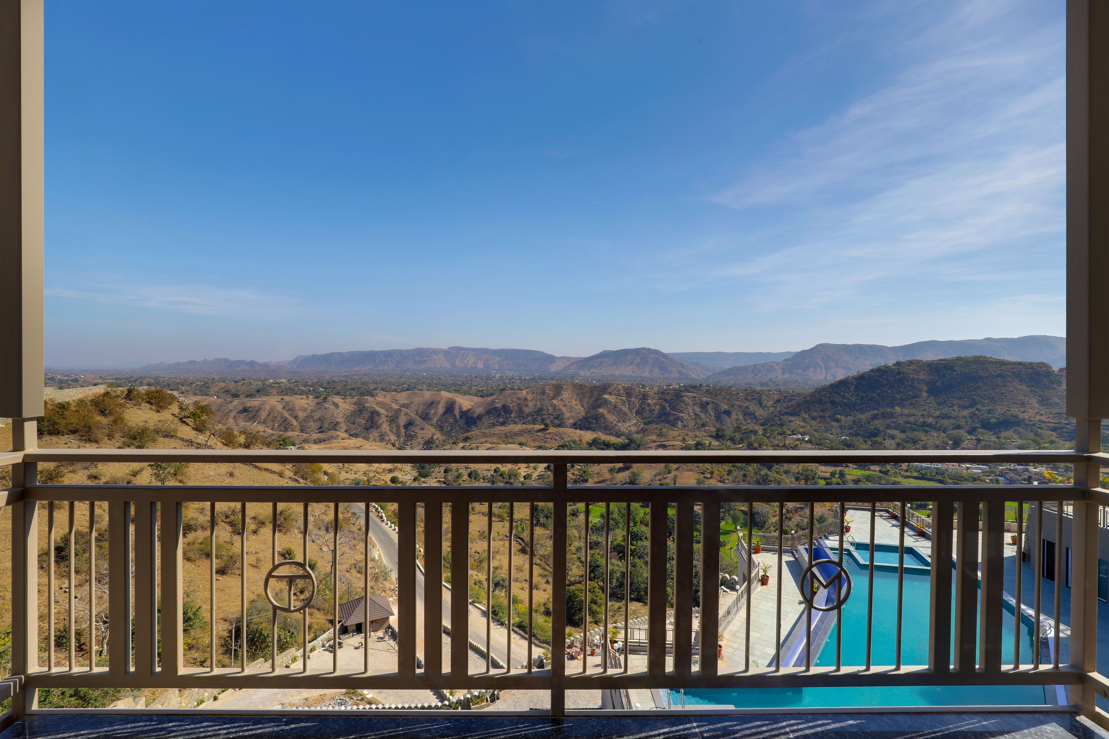A balcony with a view of a mountainous landscape and a swimming pool.