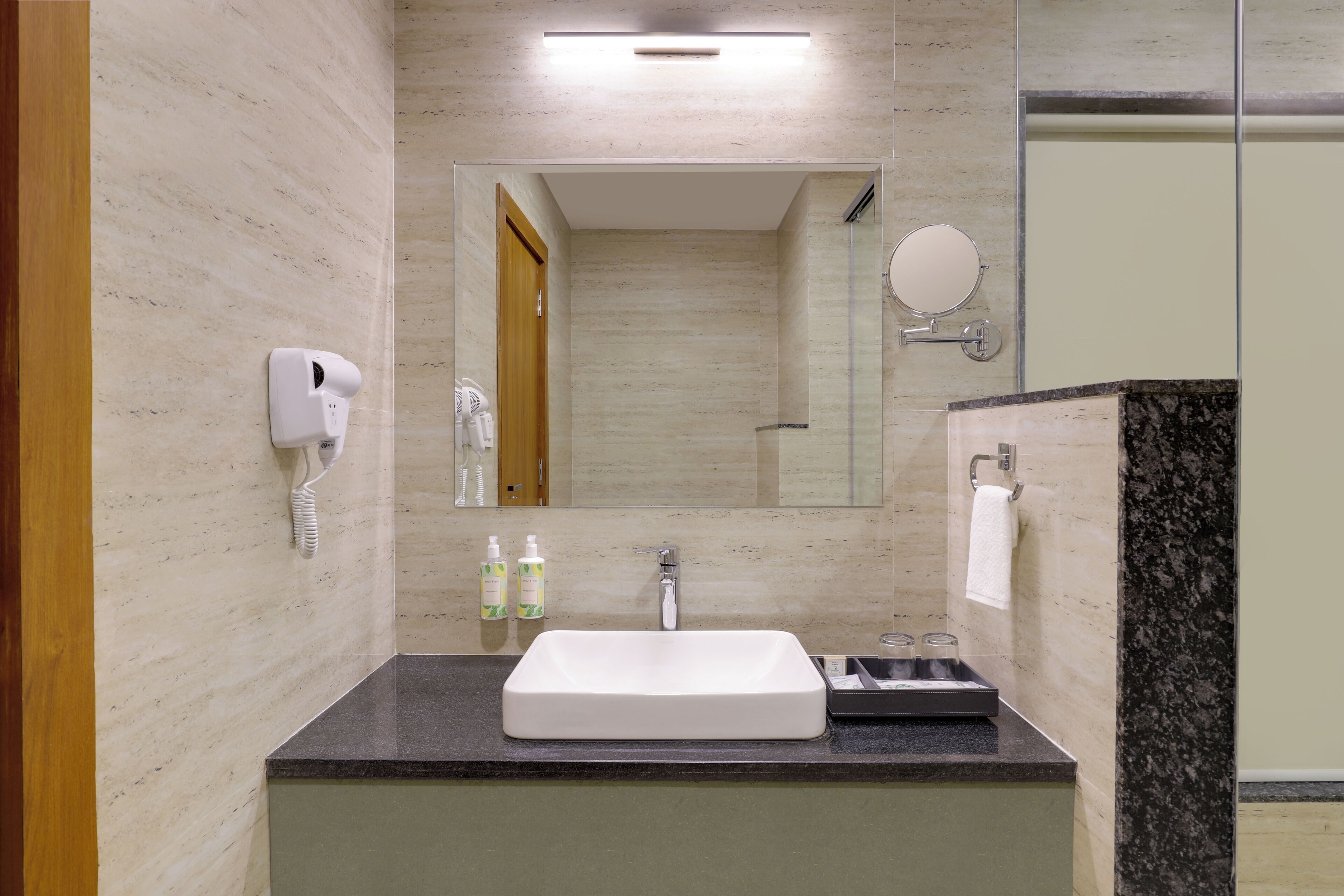 Un bagno moderno con un lavandino ampio, un soffione doccia a mano, uno specchio e un porta asciugamani.