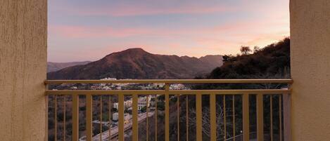 A balcony with a view of a mountain range and a town below.