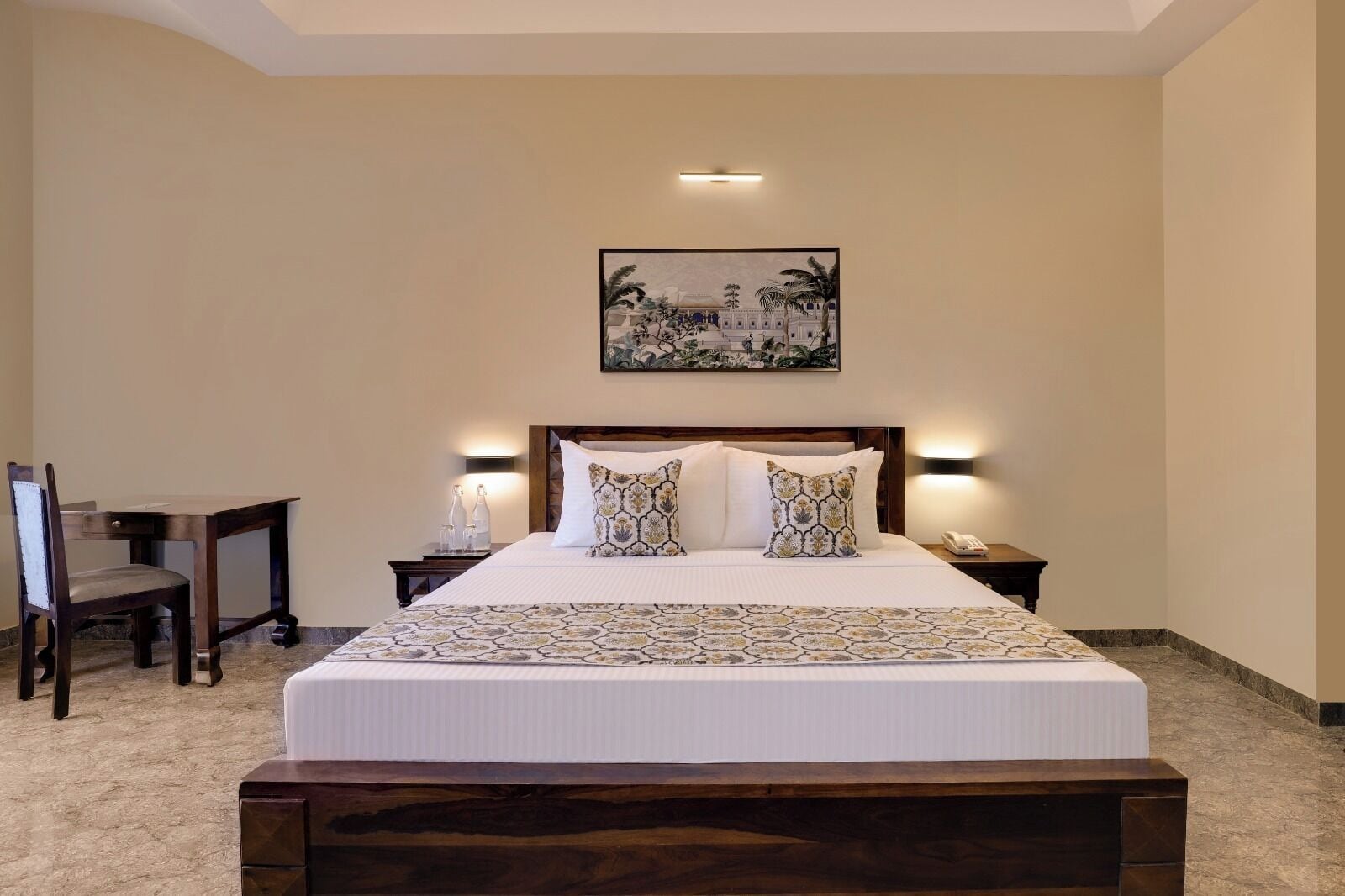 A hotel room with a large bed, two bedside tables with lamps, a wooden chair, and a painting on the wall.