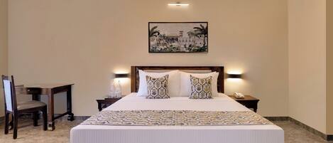 A hotel room with a large bed, two bedside tables with lamps, a wooden chair, and a painting on the wall.
