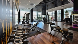 Een ruime fitnessruimte met diverse trainingsapparaten, grote ramen en een modern ontwerp.