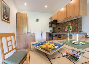 A modern kitchen with wooden cabinets, a dining table with fruit, and a magazine.