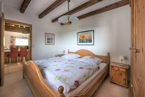 A bedroom with a wooden bed, a bedside table, a chair, and a door. - Apartment 'Ferienwohnung 1, 60qm' with Private Terrace, Private Garden and Wi-Fi (Herscheid)
