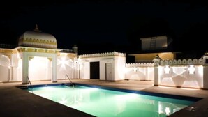 A swimming pool with a white fence and a small building with a dome. - Yash Veer Resort (Sirohi)