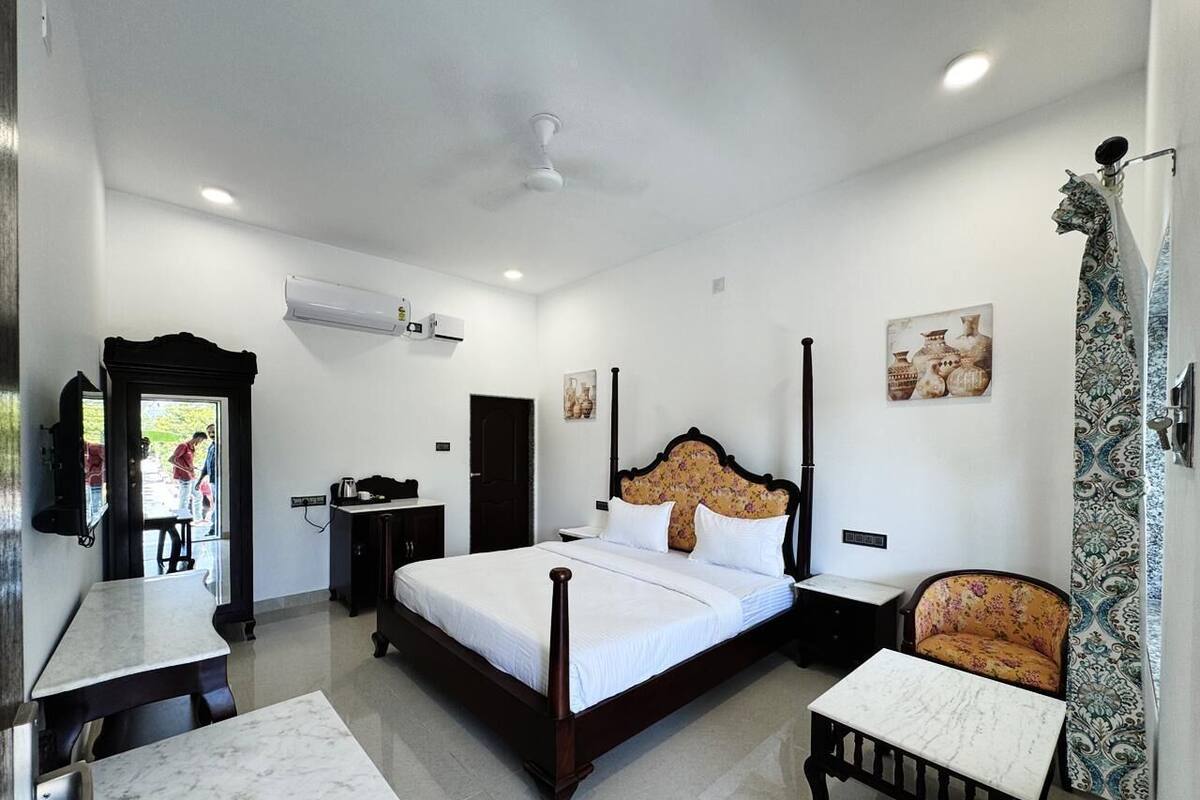 A bedroom with a bed, bedside tables, a chair, a desk, and a television.