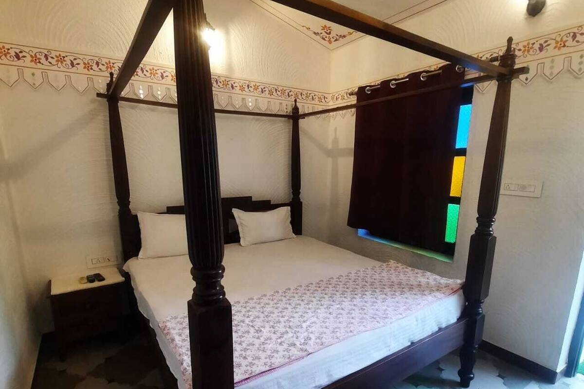 A four-poster bed with a canopy, a bedside table, and a nightstand.