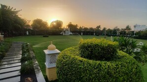 A landscaped garden with a paved walkway, neatly trimmed hedges, and a fountain. - Yash Veer Resort (Sirohi)