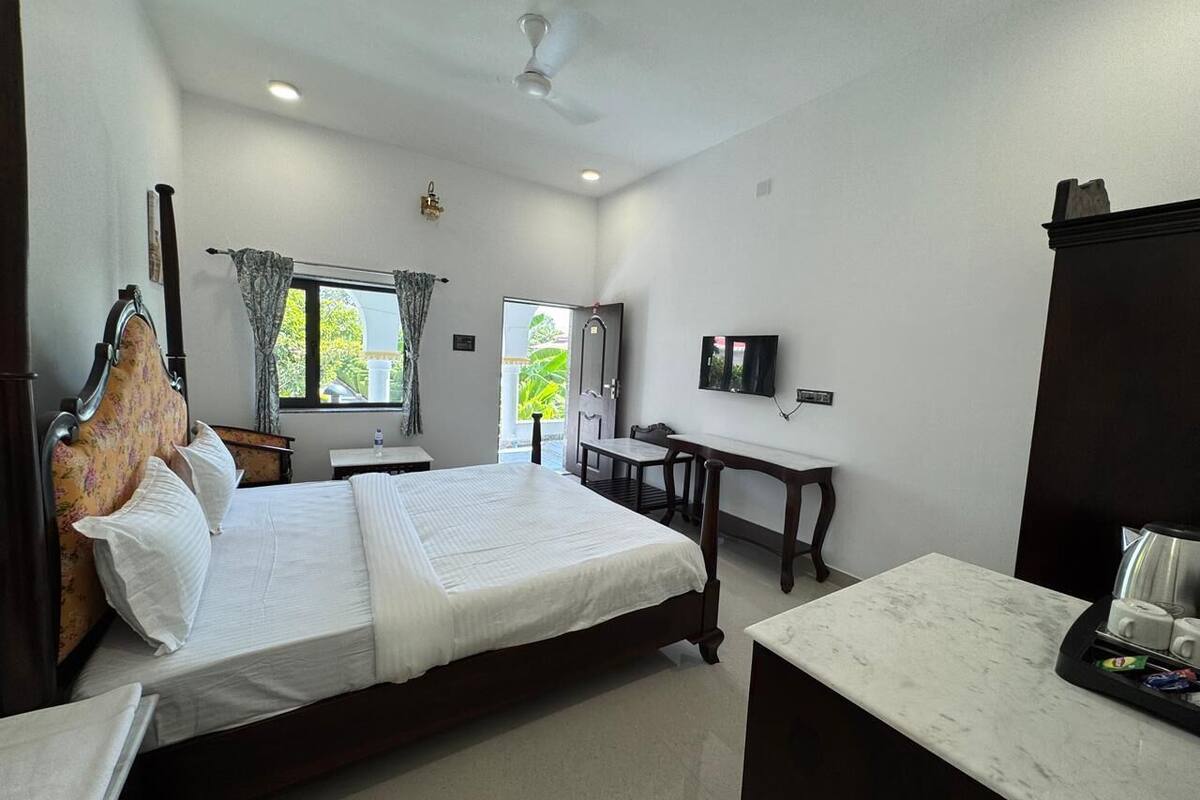 A hotel room with a bed, a desk, a television, and a window with curtains.