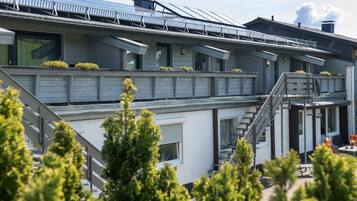 A modern building with solar panels, a staircase, and a balcony with plants.