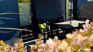 An outdoor seating area with a table and chairs, a large umbrella, and a view of a building with a dark facade and windows. - Holiday Apartment "Kathi‘s Allgäuliebe" with Mountain View, Private Terrace & Wi-Fi (Weitnau)