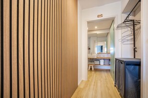A hallway with a wooden slat wall, a sink area with a mirror, and a black cabinet.