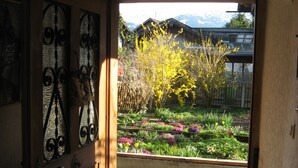 An open doorway leading to a garden with a stone pathway and a wooden door with metal decorations. - Holiday Apartment "Gästehaus Marianne" with Mountain View, Shared Terrace and Wi-Fi (Farchant)
