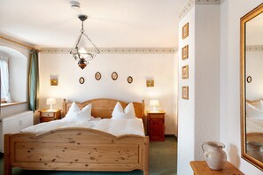 Une chambre à coucher bien rangée, avec un lit en bois, des lampes de chevet, un miroir et un vase posé sur une table.