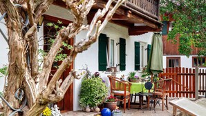 A rustic outdoor seating area with a table and chairs, surrounded by potted plants and a wooden fence. - Holiday Apartment "Gästehaus Marianne" with Mountain View, Shared Terrace and Wi-Fi (Farchant)