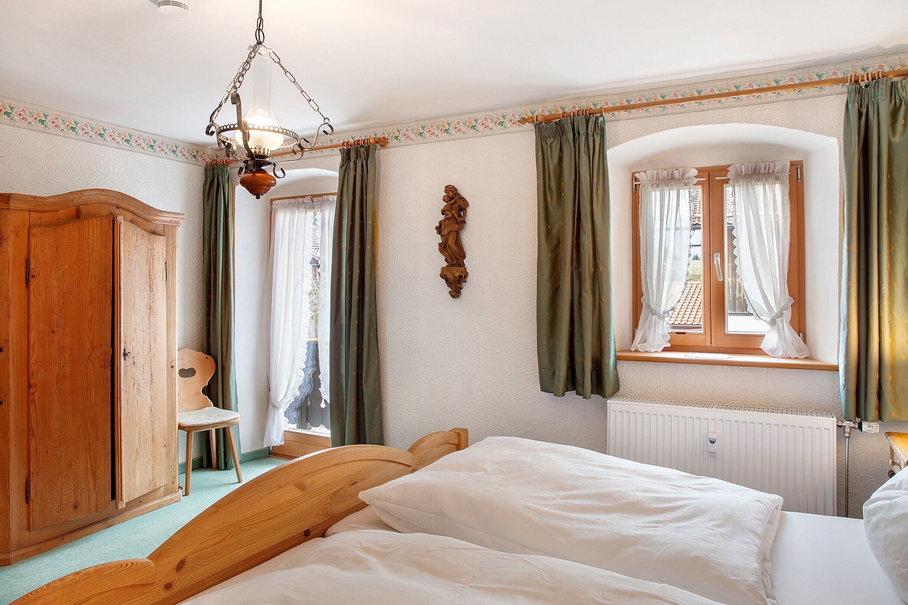 Ein Schlafzimmer mit einem Holzbett, einem Heizkörper, einem Holzschrank und einem Stuhl.