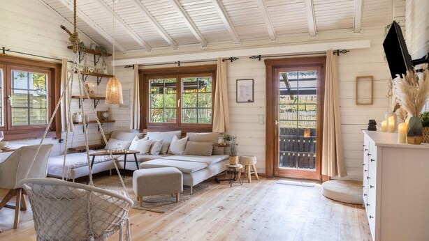 A cozy room with a sofa, a hanging chair, a dining area, and a large window with a view.