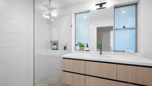 Een moderne badkamer met een grote spiegel, een wastafel en een douchehoek.