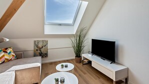 Un salon moderne doté d’une verrière, d’un téléviseur à écran plat, d’un canapé, d’une table basse et d’un tableau.
