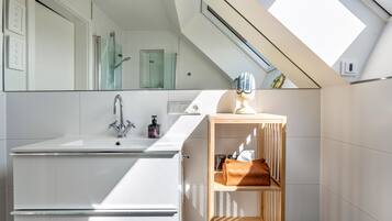 A modern bathroom with a skylight, a sink, and a wooden shelf.
