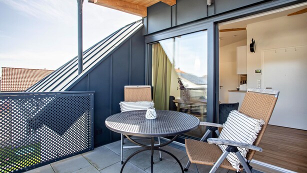 Un balcon avec une table ronde et deux chaises, un plafond en bois et une vue sur le ciel.