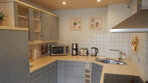 A modern kitchen with grey cabinets, a microwave, a coffee maker, and a toaster. - Holiday Home 'Viktoria' with Private Terrace, Garden, and Wi-Fi (Koblenz)