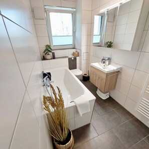 A modern bathroom with a bathtub, toilet, and sink. - Apartment 'Am Hochwald' with Mountain View, Private Terrace and Wi-Fi (Reinhardtsdorf-Schöna)