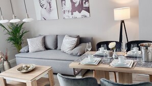 Ein modernes Wohnzimmer mit grauem Sofa, einem Holztisch und einem Essbereich mit Stühlen und Tisch.