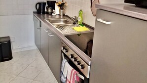 Une cuisine équipée d’un évier en acier inoxydable, d’une cuisinière et d’un four à micro-ondes.