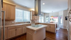 Una cocina amplia con armarios de madera, una isla central y un gran ventanal que proporciona luz natural.