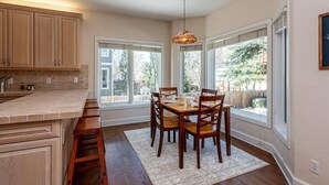 Una cocina con armarios de madera, una mesa de comedor con sillas y ventanas amplias que ofrecen vistas al exterior.