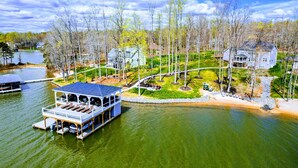 A lakeside property with a dock, a boat house, and a well-maintained lawn. - Private Paradise 2 Story Dock, Beach, Hot Tub (Mineral)