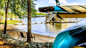 A lakeside view with a dock, chairs, and a boat. - Private Paradise 2 Story Dock, Beach, Hot Tub (Mineral)