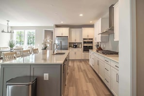 Una cocina moderna con armarios blancos, electrodomésticos de acero inoxidable y una isla central.