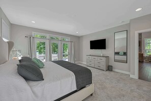 A bedroom with a large bed, a dresser, a TV, and a sliding glass door leading to a balcony. - Lakefront Lake Anna with Cove, Dock, Deck, Hot Tub (Mineral)