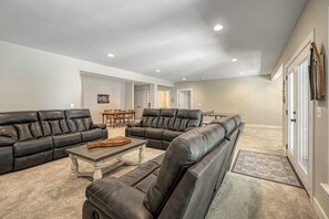 A spacious living room with leather sofas, a wooden coffee table, and a dining area with a table and chairs.