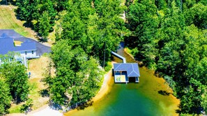 An aerial view of a house surrounded by dense forest and a body of water. - Lakefront Lake Anna with Cove, Dock, Deck, Hot Tub (Mineral)