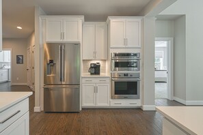 A modern kitchen with white cabinetry, stainless steel appliances, and a wood floor.