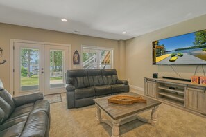 A living room with a leather sofa, a coffee table, and a television mounted on the wall.