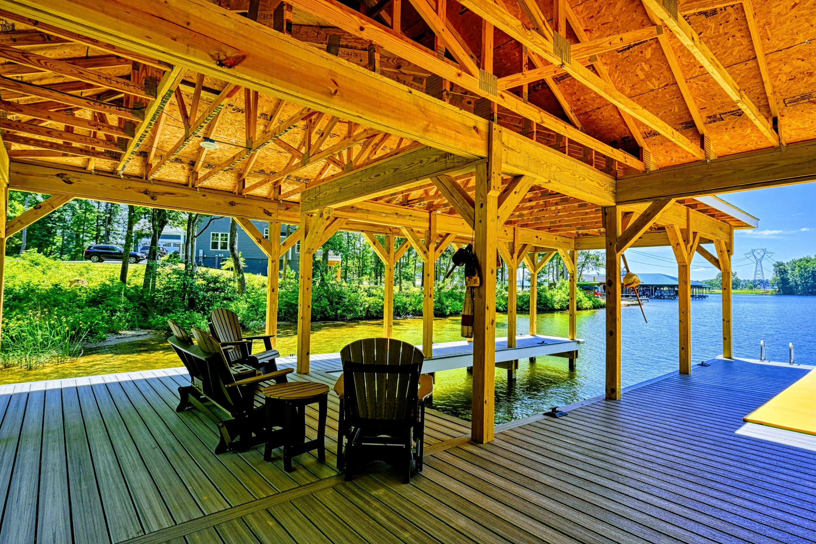 A covered outdoor deck with wooden furniture and a view of a lake.