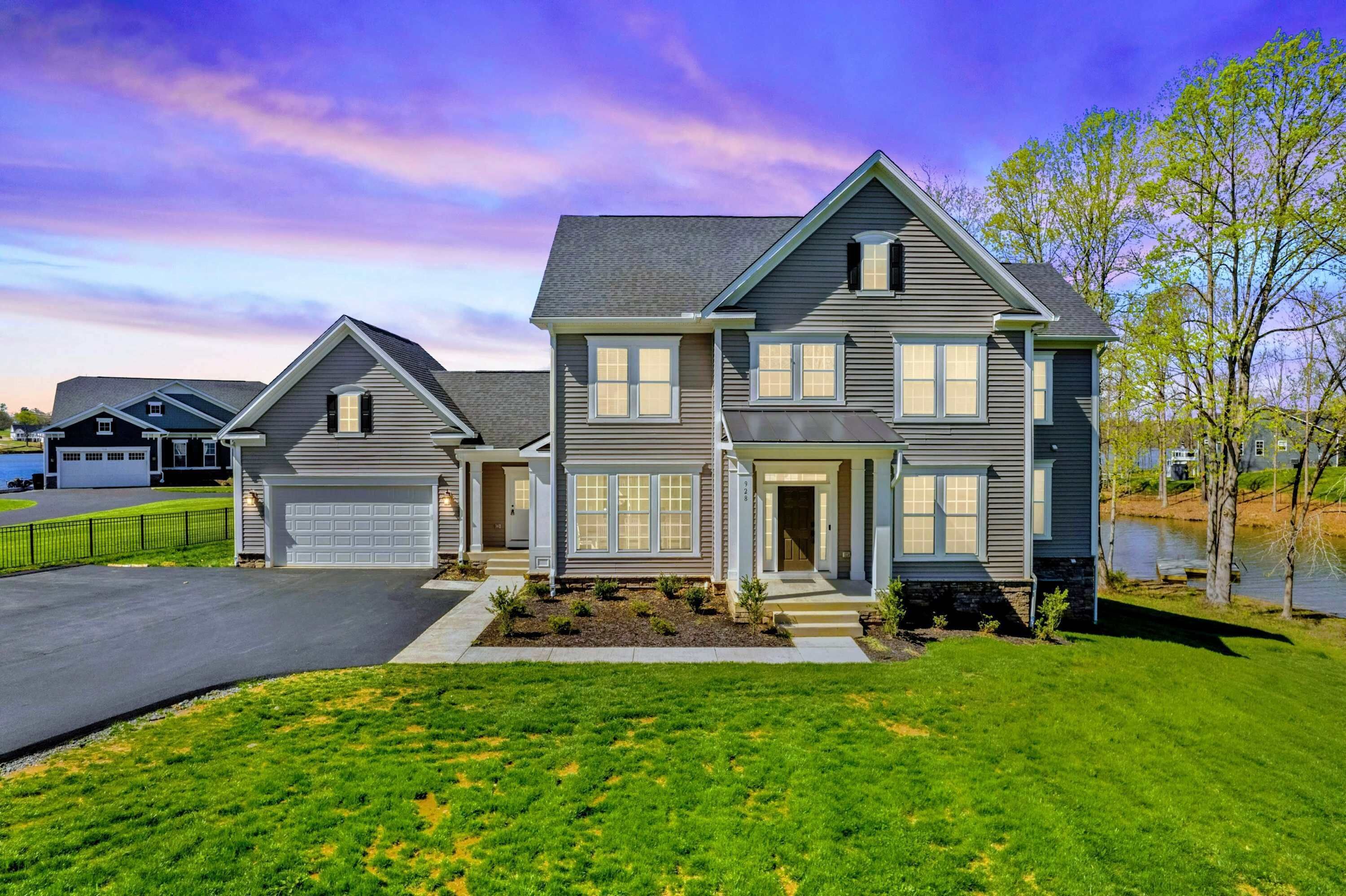 A two-story house with a garage, a driveway, and a well-maintained lawn.