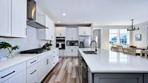A modern kitchen with white cabinetry, stainless steel appliances, and a large island. - Private Cove Lakefront Lake Anna Beach & Dock (Mineral)