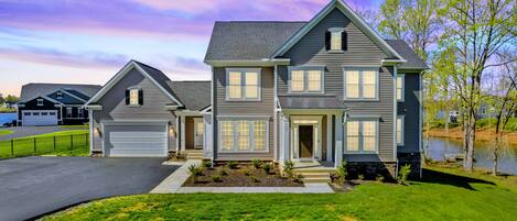 A two-story residential house with a garage, a front porch, and a well-maintained lawn.