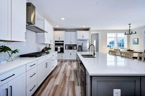 A modern kitchen with white cabinetry, a central island, and a dining area with a view.