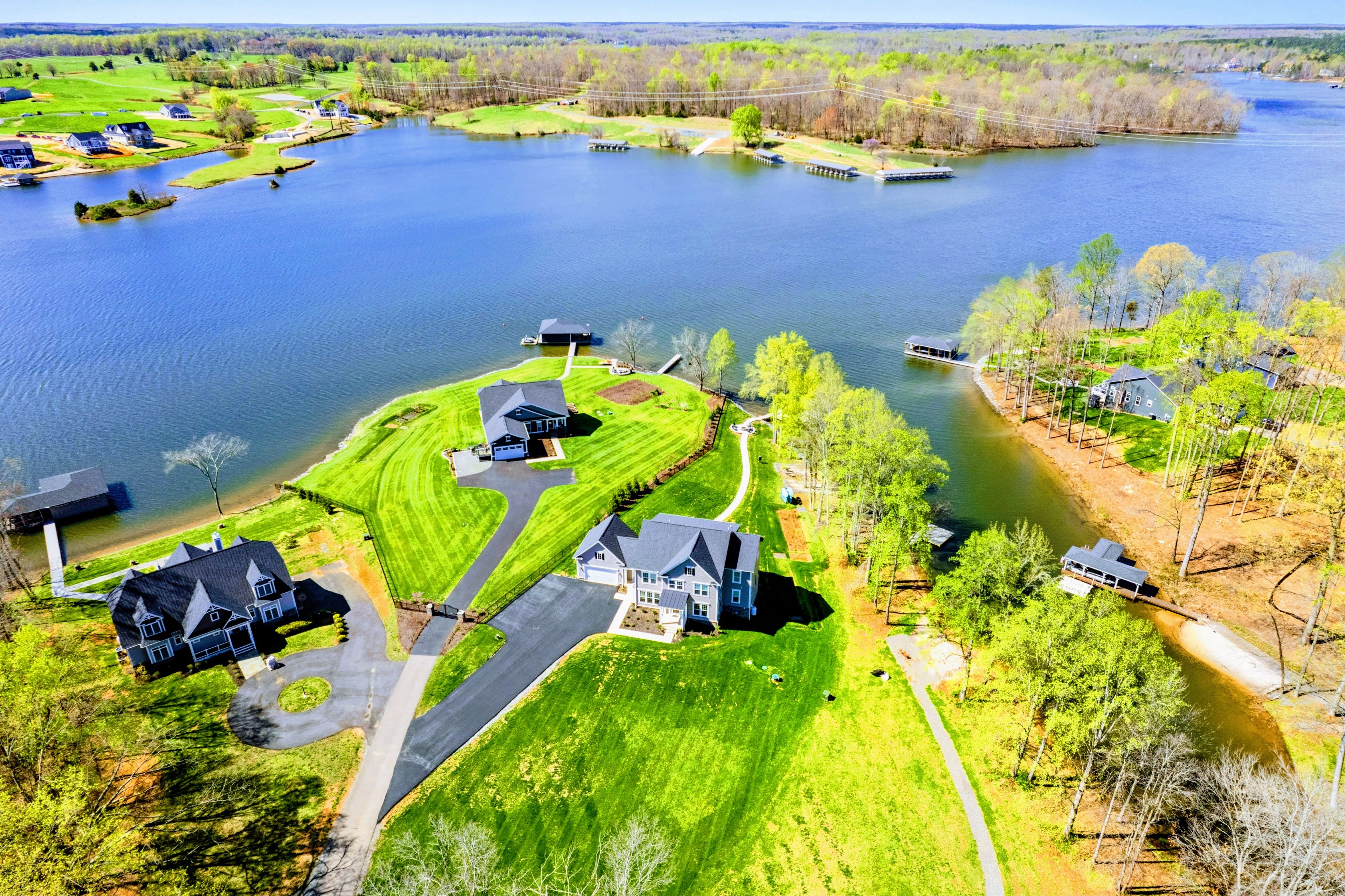 Zona residencial con casas cerca de un lago, con céspedes cuidados y cielo despejado.