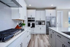 Una cocina moderna con gabinetes blancos, electrodomésticos de acero inoxidable y piso de madera.