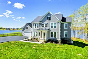 A two-story house with a garage, a front porch, and a view of a lake.